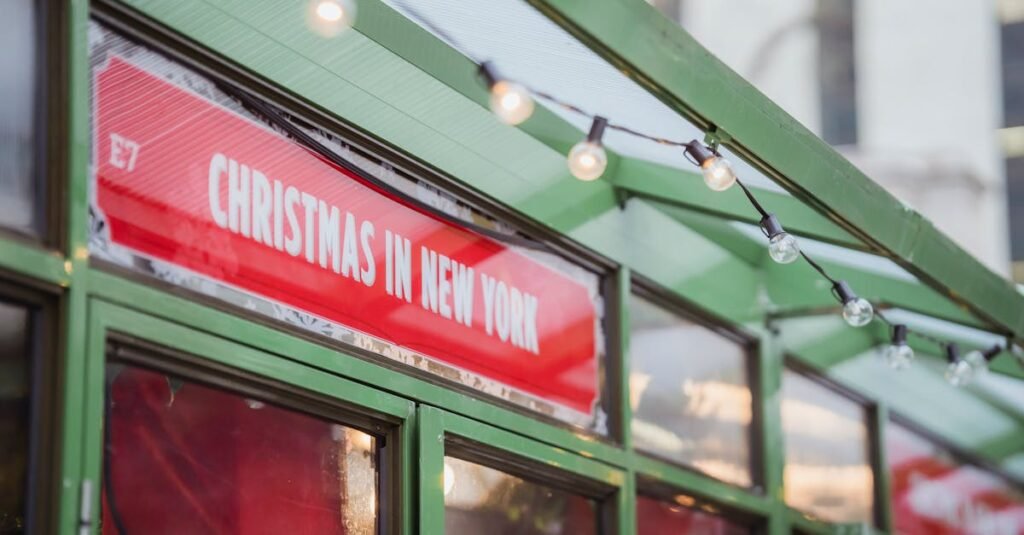 low angle red signboard with christmas in new york inscription hanging on glass showcase of shop on