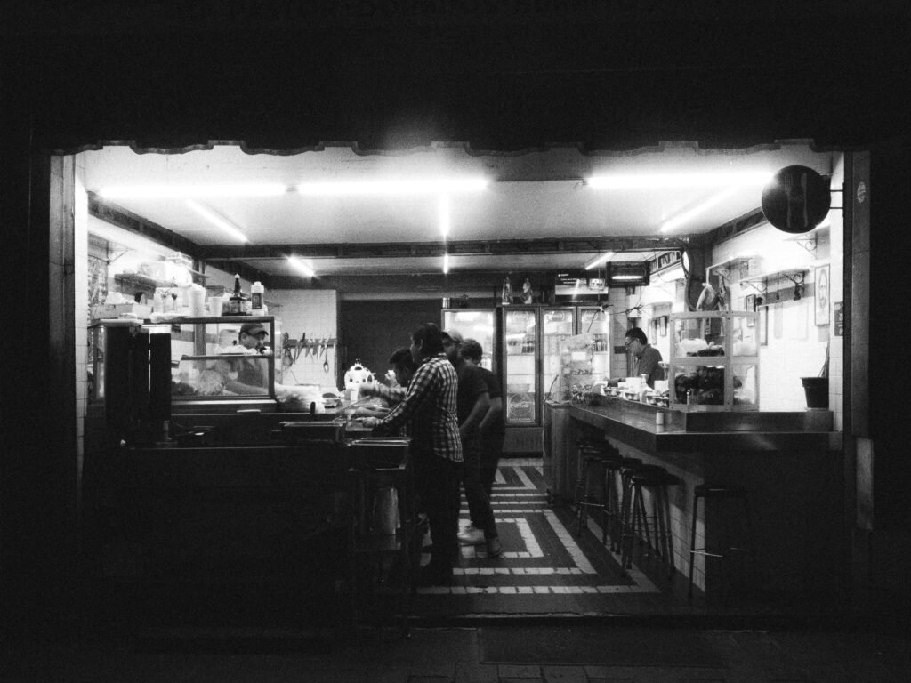 Black and white photo of a bustling taco stand in León, Mexico at night.